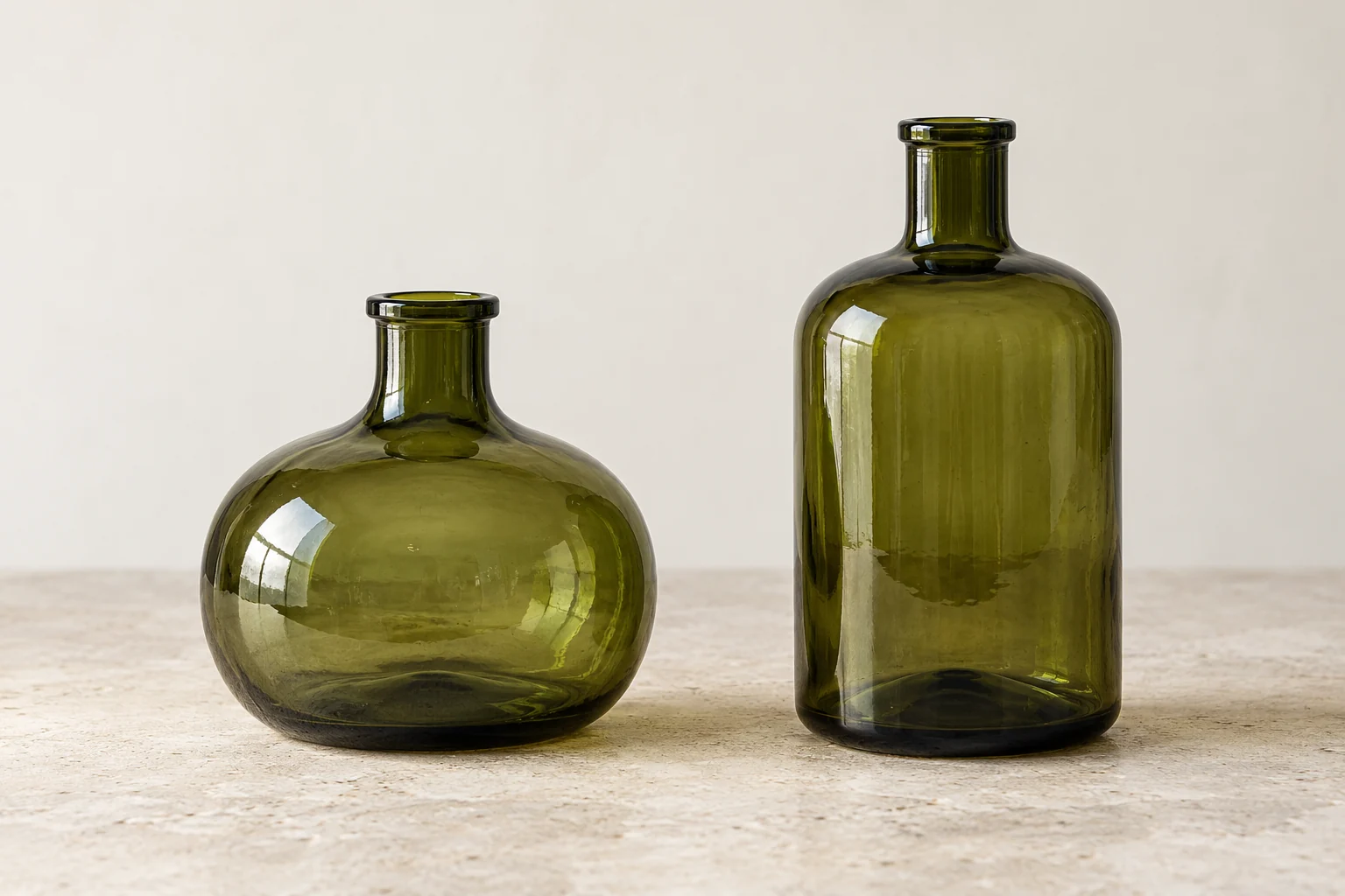 Two contemporary glass form studies, one low and rounded and one taller and cylindrical, shown side by side.